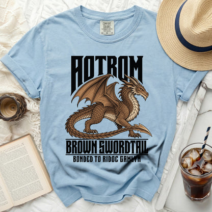 Light blue t-shirt with a brown dragon graphic and text "AOTROM BROWN SWORDTAIL BONDED TO RIDOC GAMLYN".
