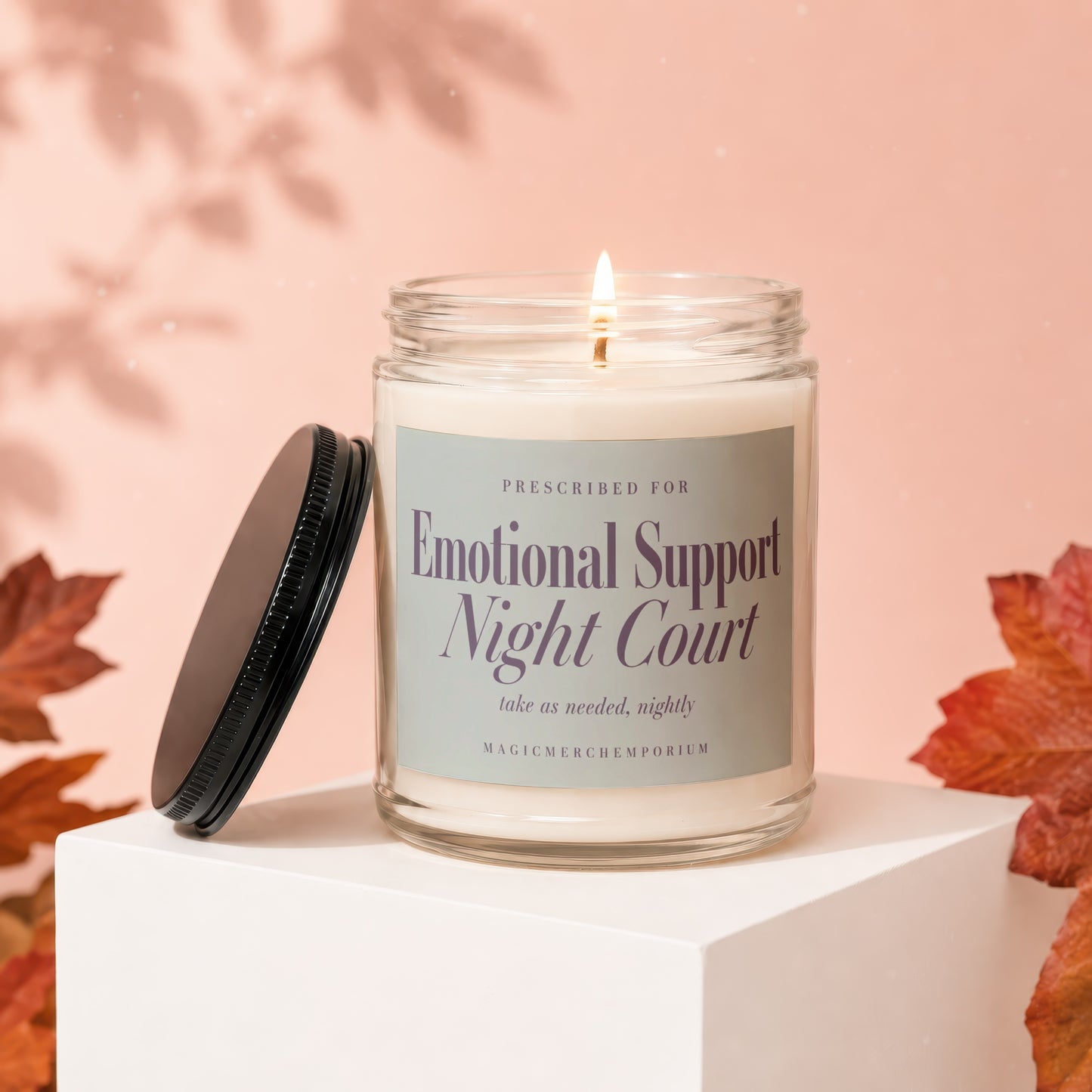 Candle labeled "Emotional Support Night Court" in a clear jar with a lit wick.