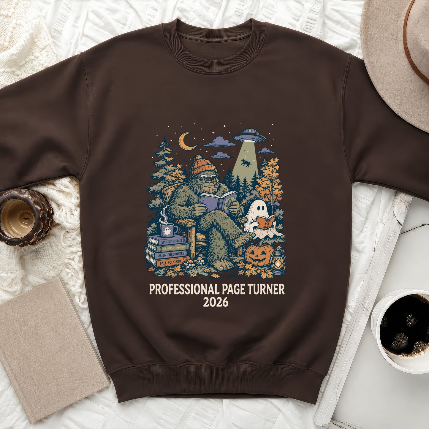 Bigfoot reads books with UFO, ghost, and pumpkin. "Professional Page Turner 2026".