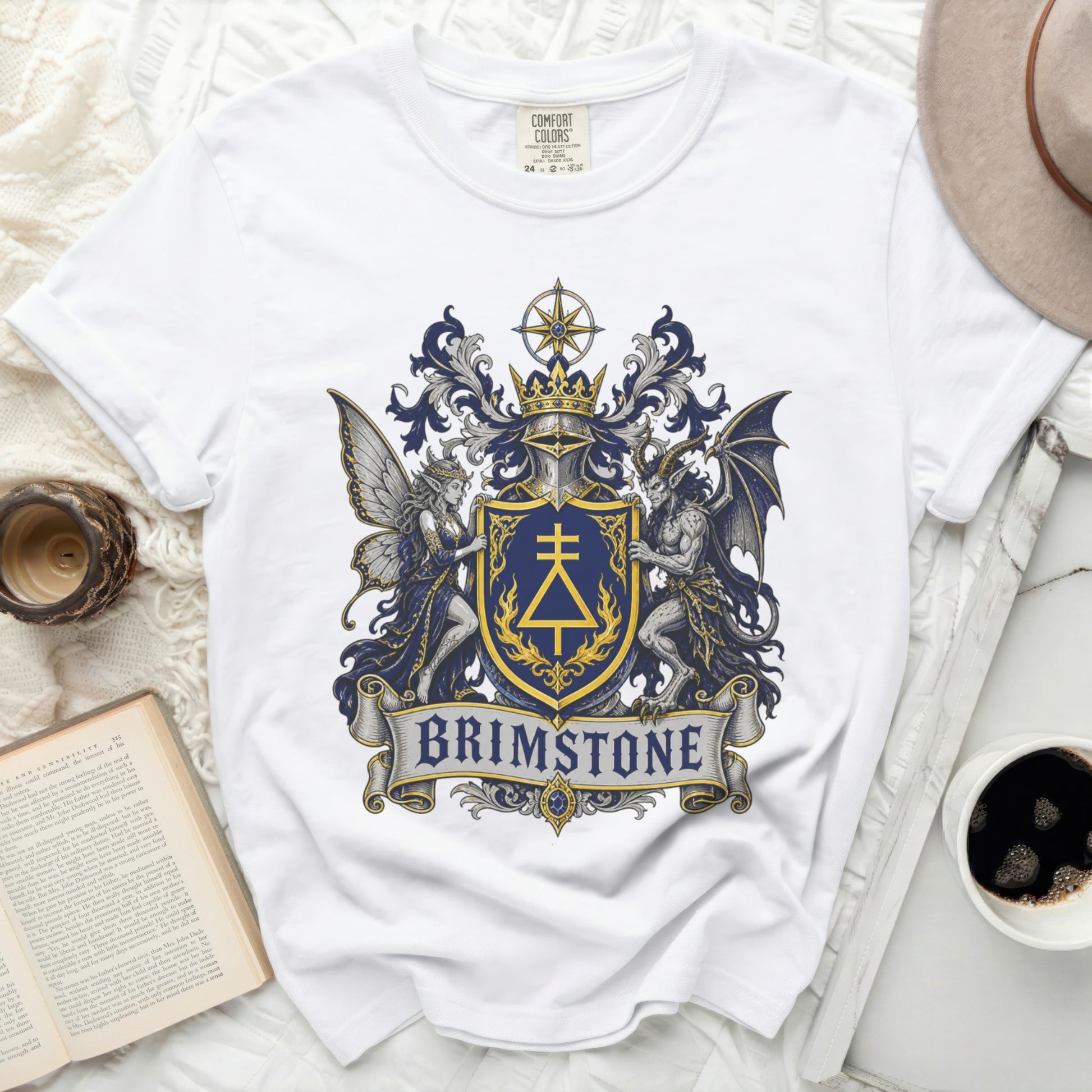 White t-shirt with a blue and gold crest featuring a fairy, a dragon, and the word BRIMSTONE.