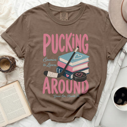 Brown t-shirt with "Pucking Around Enemies to Lovers" graphic and books.