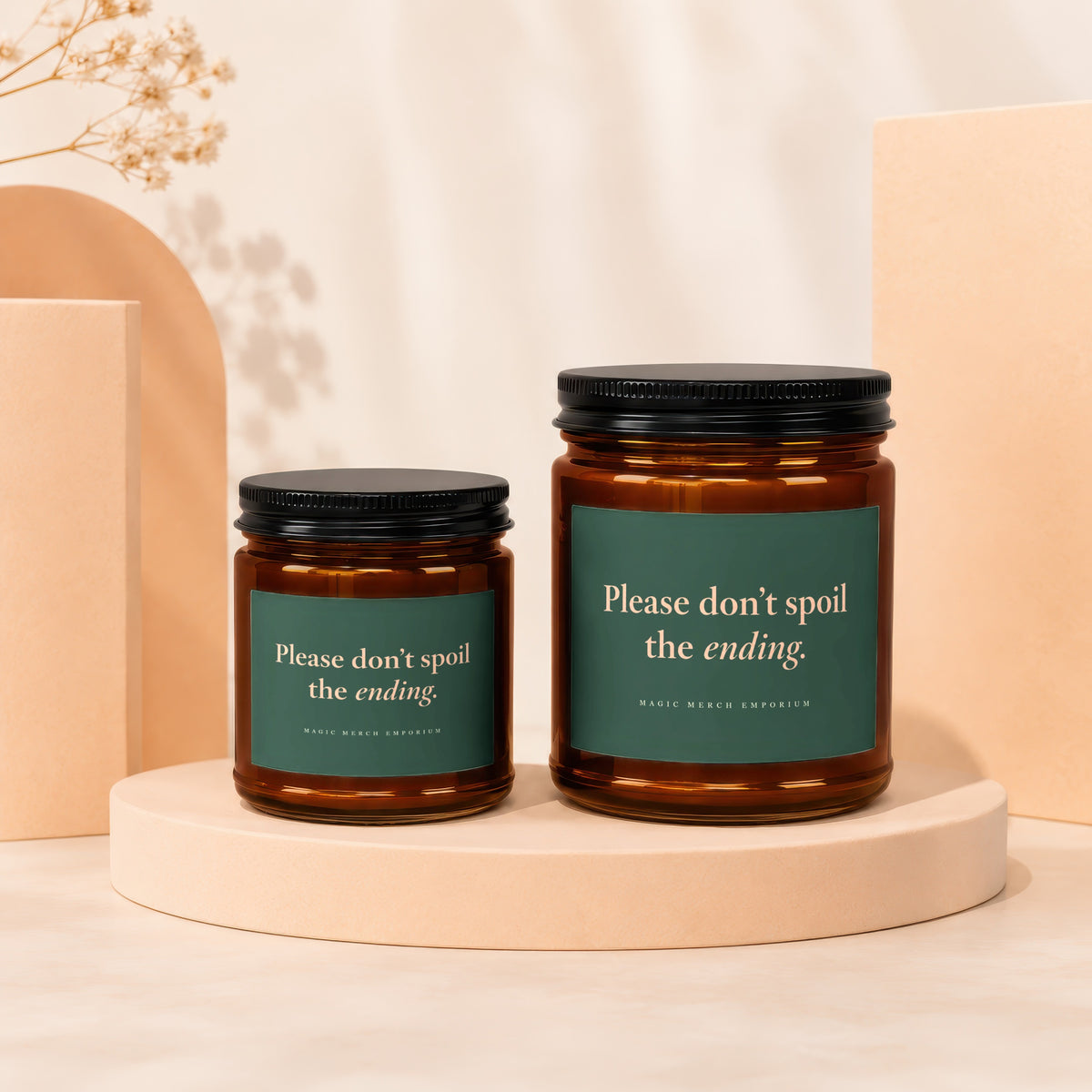Two amber glass candle jars with black lids and green labels reading Please don't spoil the ending.