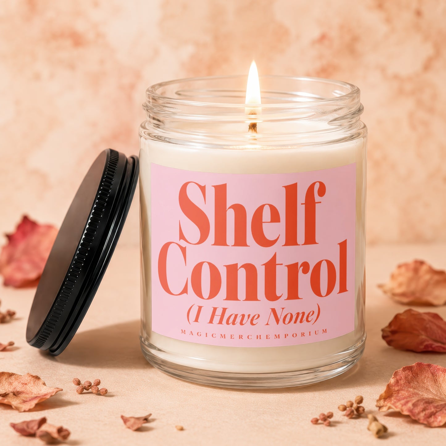 Lit candle in glass jar with pink label reading "Shelf Control (I Have None)".
