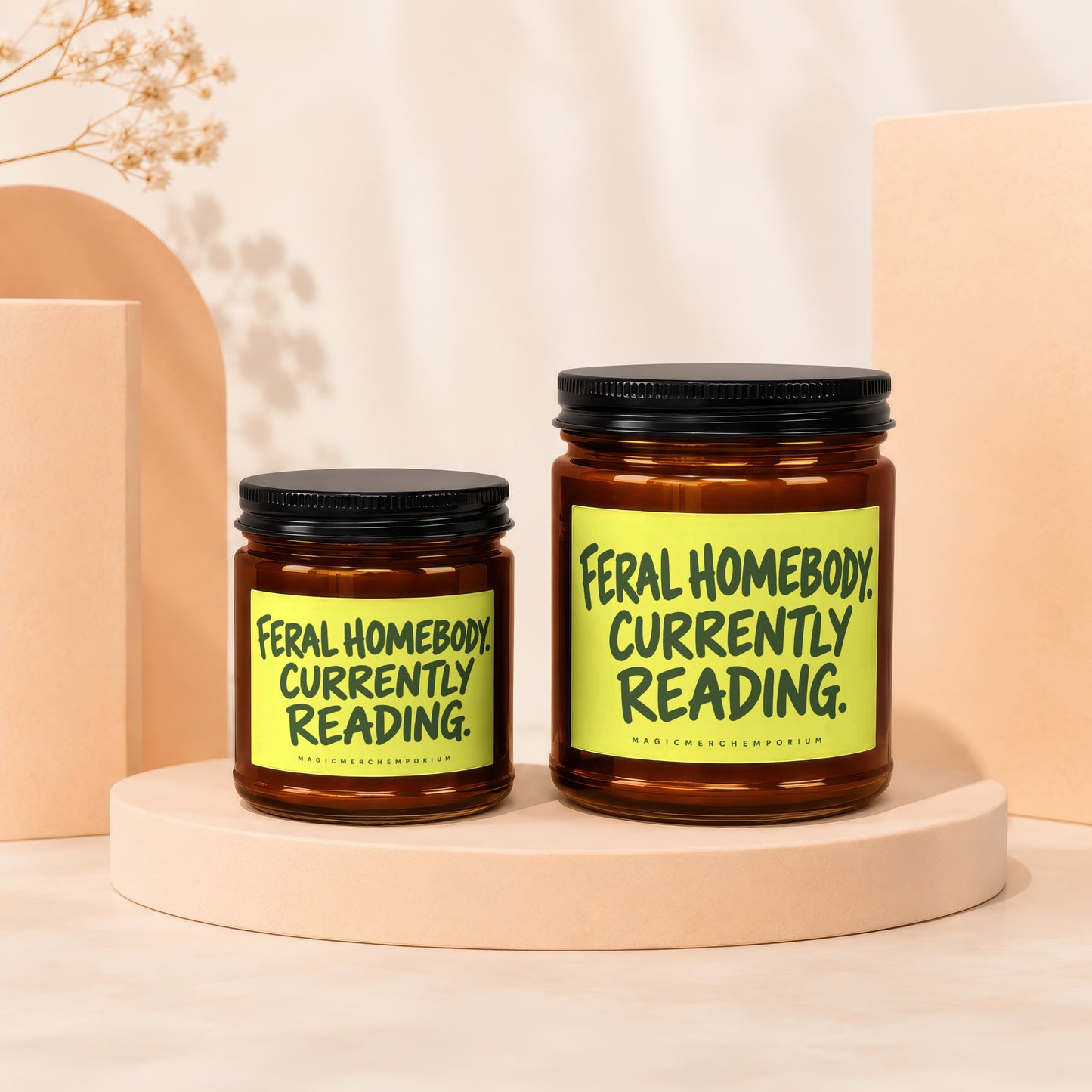 Two amber jars with black lids, one larger than the other, each labeled "Feral Homebody. Currently Reading."
