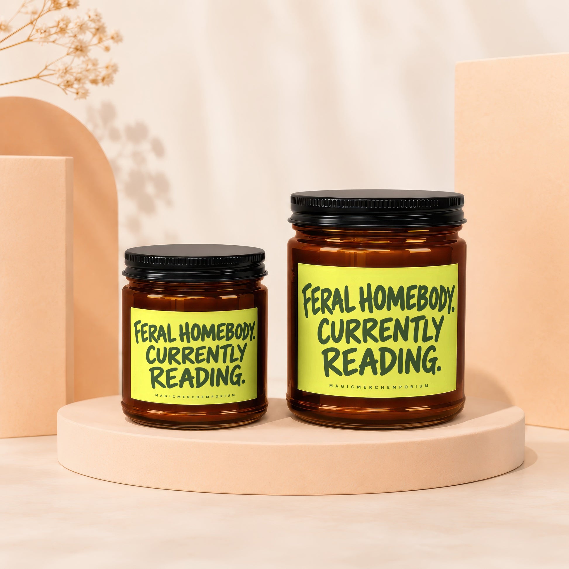 Two amber jars with black lids, one larger than the other, each labeled "Feral Homebody. Currently Reading."