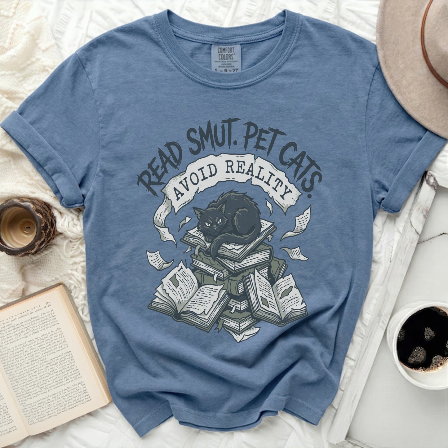 Blue t-shirt with a black cat on a stack of books, "Read Smut. Pet Cats. Avoid Reality."