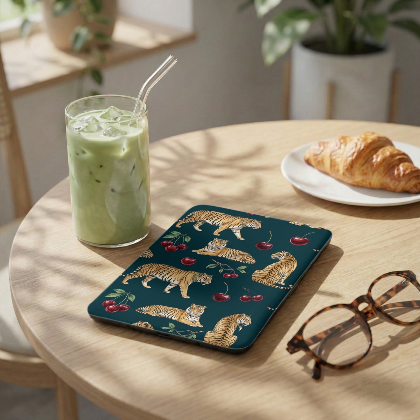 Dark teal tablet case with tiger and cherry pattern, next to a matcha drink.