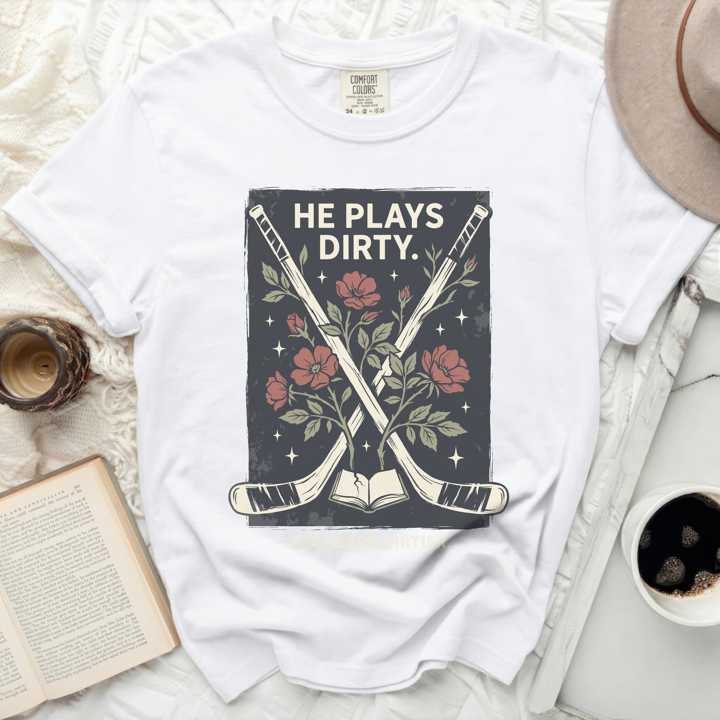 White t-shirt with crossed hockey sticks, flowers, and "HE PLAYS DIRTY" text.