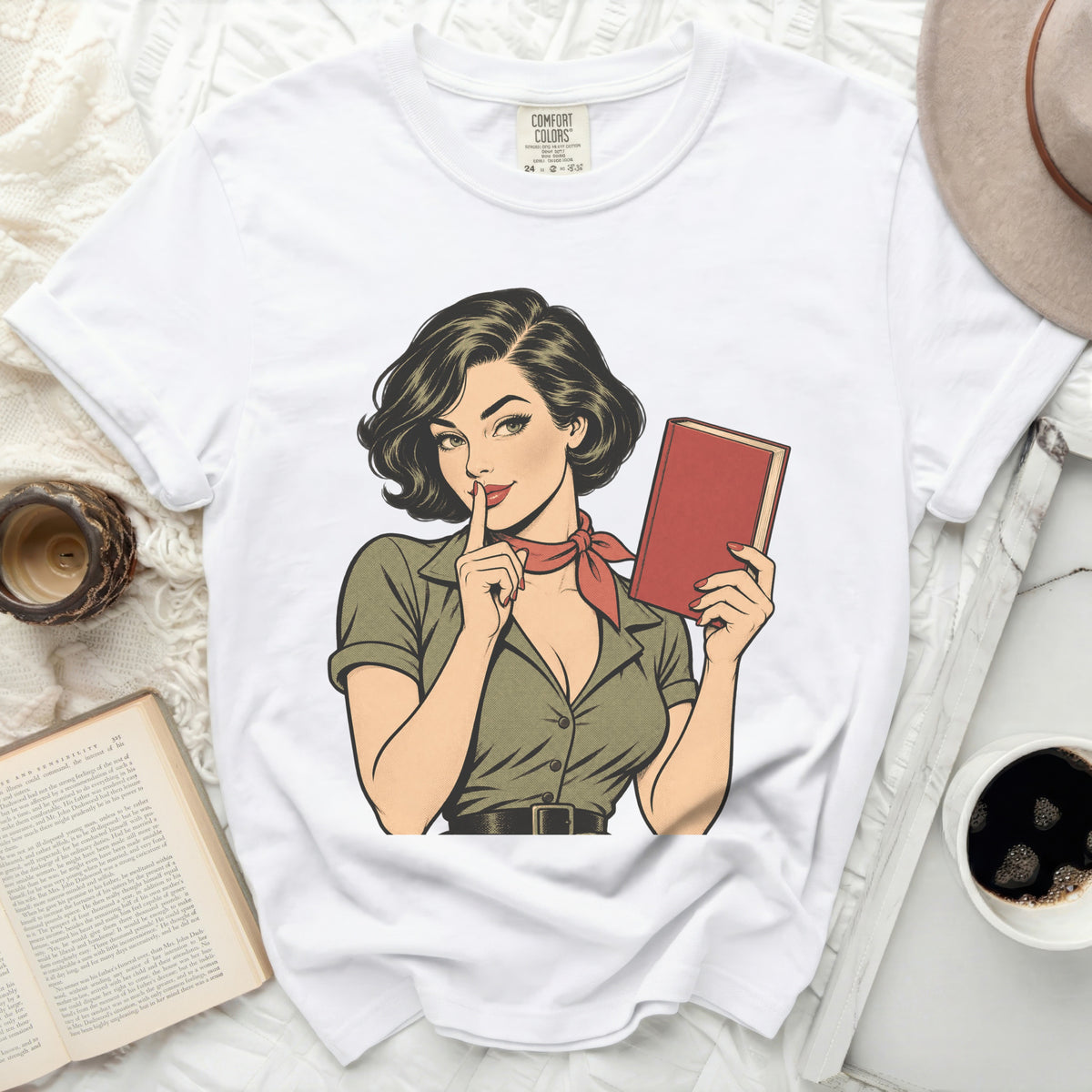 White Comfort Colors t-shirt with retro comic art of a woman holding a book and shushing.
