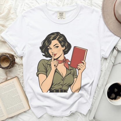 White Comfort Colors t-shirt with retro comic art of a woman holding a book and shushing.