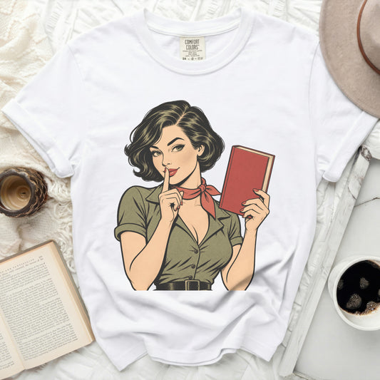 White Comfort Colors t-shirt with retro comic art of a woman holding a book and shushing.