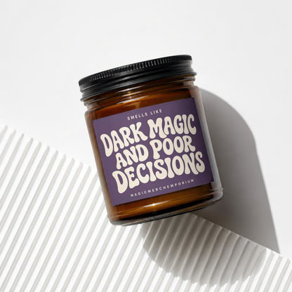 Amber jar candle with purple label that reads "Smells Like Dark Magic And Poor Decisions".