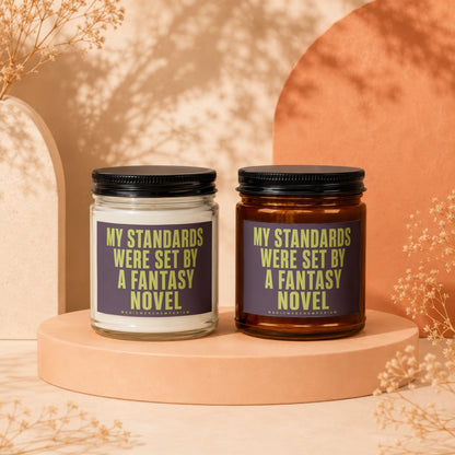 Two candles, one clear, one amber, featuring "My standards were set by a fantasy novel" text.
