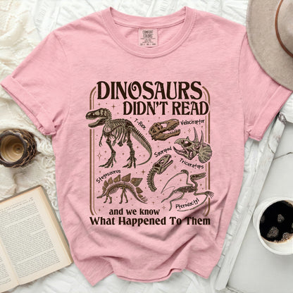 Pink t-shirt with "Dinosaurs Didn't Read" text and dinosaur skeletons.