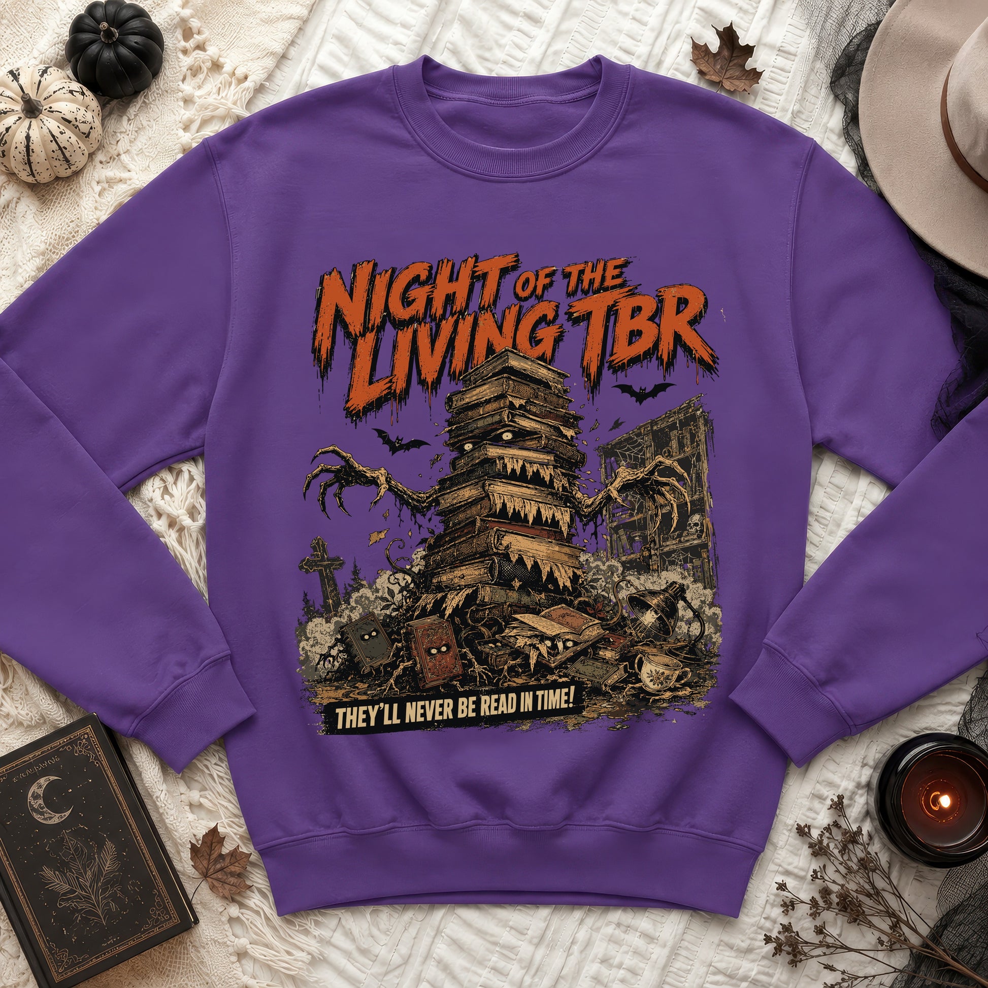 Purple sweatshirt with "Night of the Living TBR" text and a stack of sentient books.