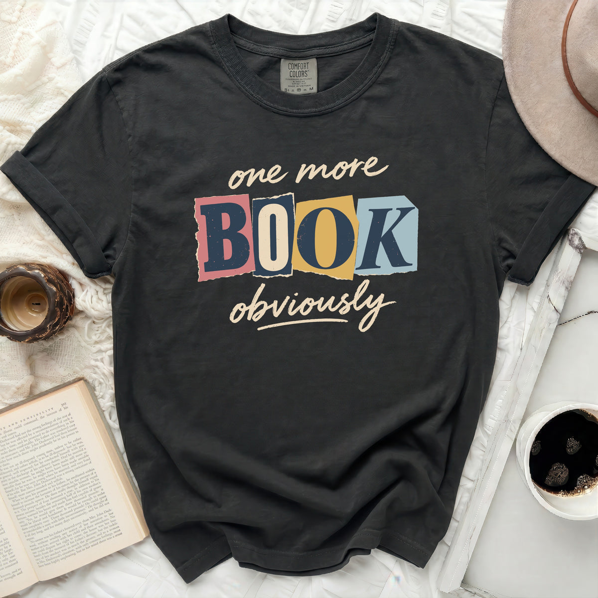 Charcoal t-shirt with "one more BOOK obviously" text in distressed colorful blocks.