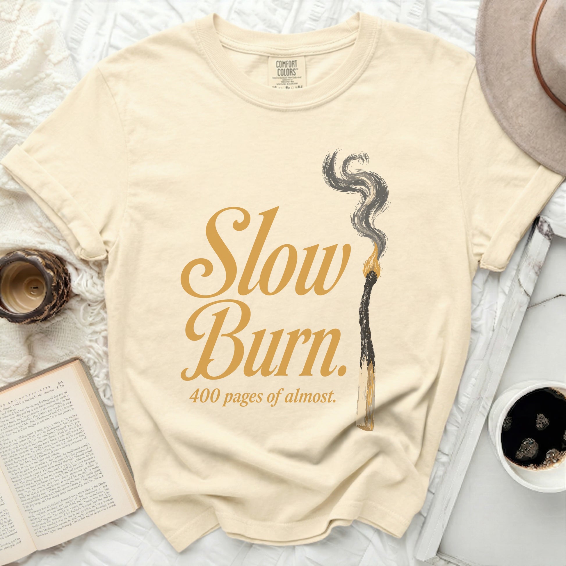 Cream t-shirt with "Slow Burn. 400 pages of almost." text and burnt match.