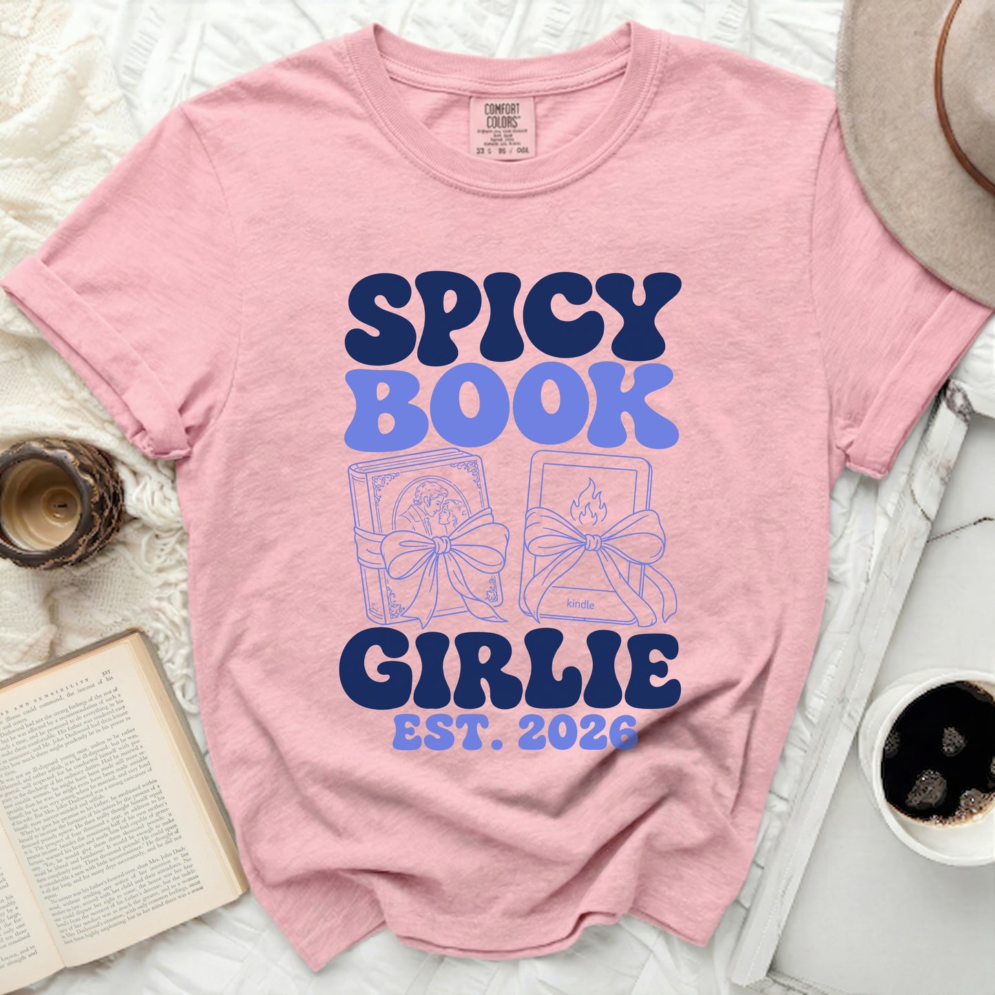 Pink t-shirt with "Spicy Book Girlie Est. 2026" and book illustrations.