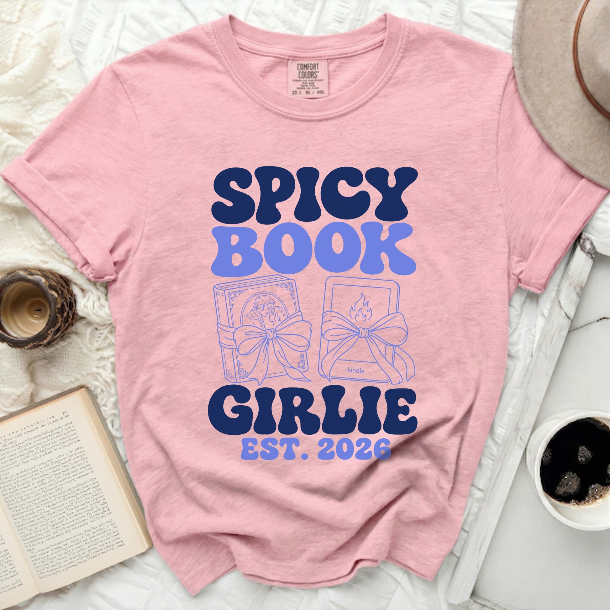 Pink t-shirt with "Spicy Book Girlie Est. 2026" and book illustrations.