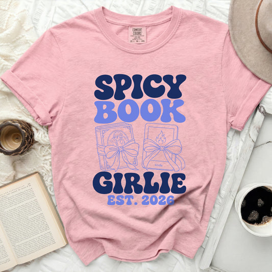 Pink t-shirt with "Spicy Book Girlie Est. 2026" and book illustrations.