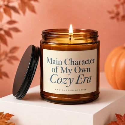 Burning amber candle with lid off, reading "Main Character of My Own Cozy Era".