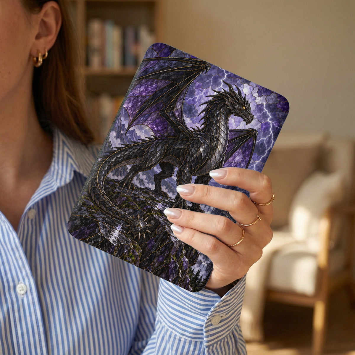 Black dragon against purple lightning storm on a detailed book cover held by a person.