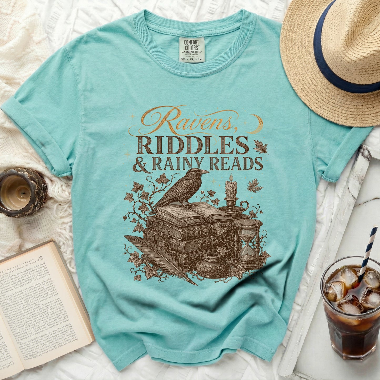 Ravens, Riddles & Rainy Reads graphic on a teal t-shirt.