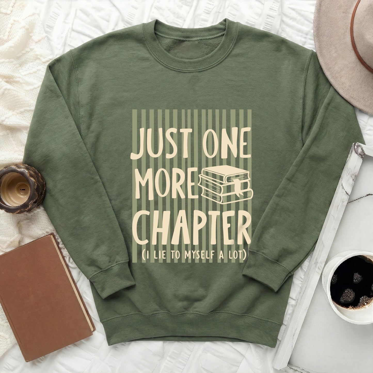 Green sweatshirt with "Just One More Chapter" text and book graphic.