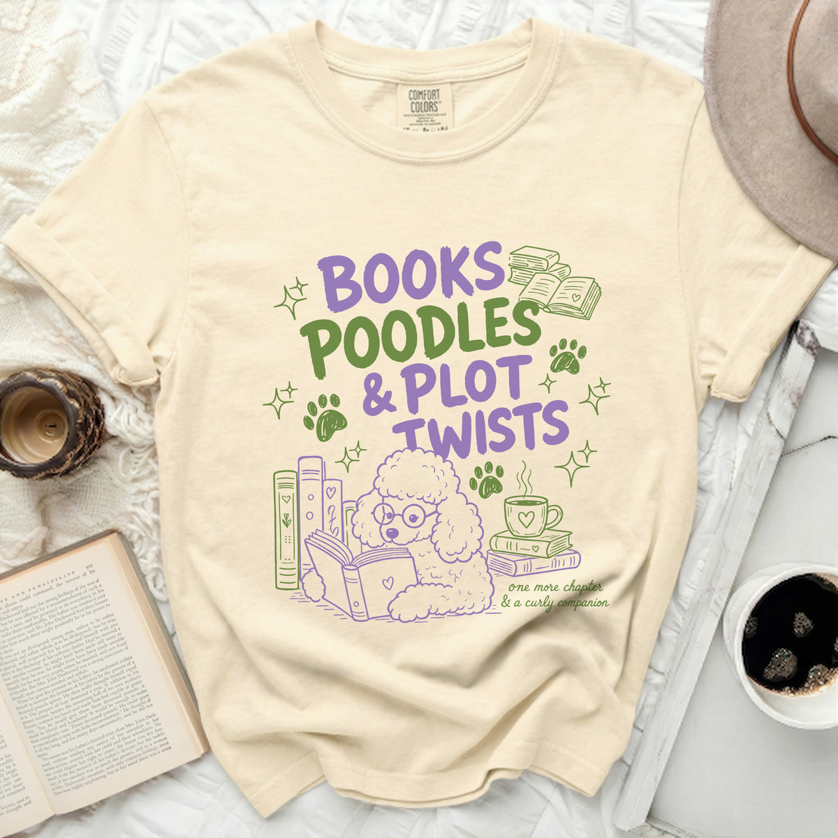 Cream t-shirt with purple and green design: "BOOKS POODLES & PLOT TWISTS".
