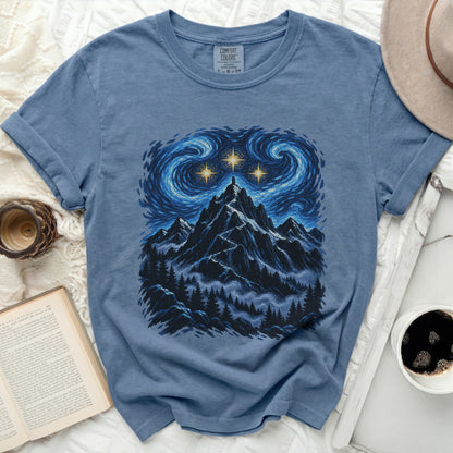 Blue t-shirt with mountain, trees, and starry sky graphic.