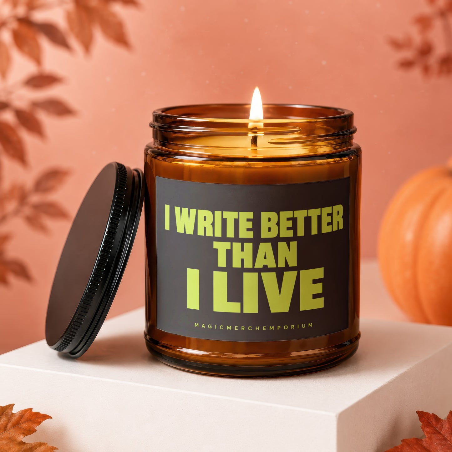 Amber jar candle with lit wick, reading "I Write Better Than I Live".