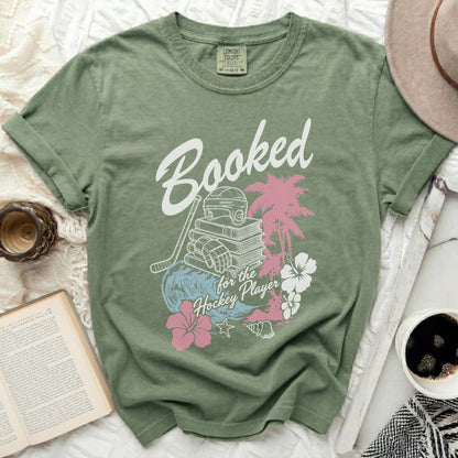 Green t-shirt with "Booked for the Hockey Player" text and hockey/tropical graphics.