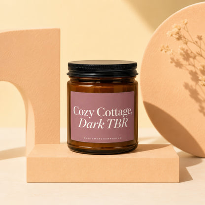 Amber jar candle labeled "Cozy Cottage, Dark TBR" from MagicMerchEmporium.
