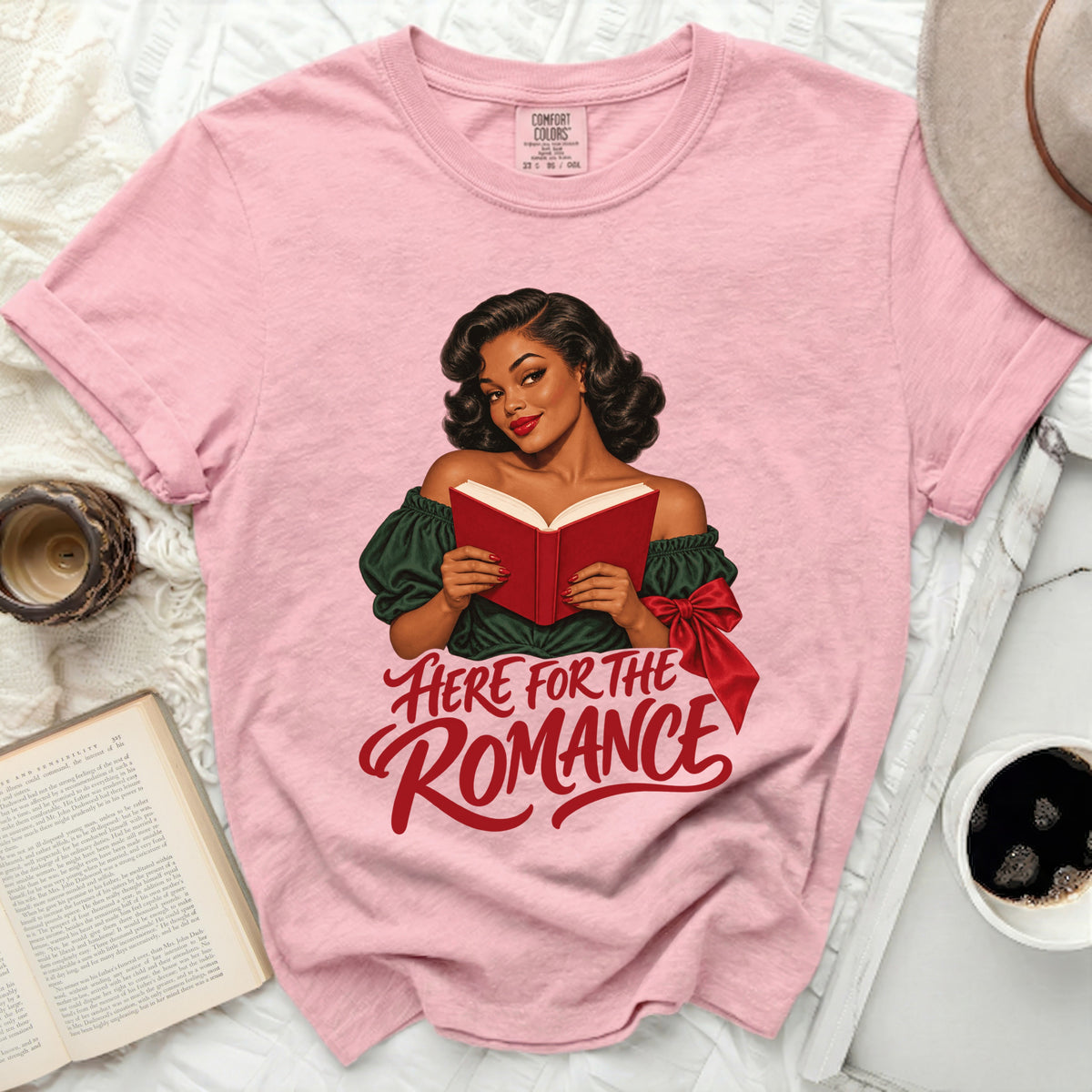 Pink t-shirt with a woman reading a book and the text "Here for the Romance".
