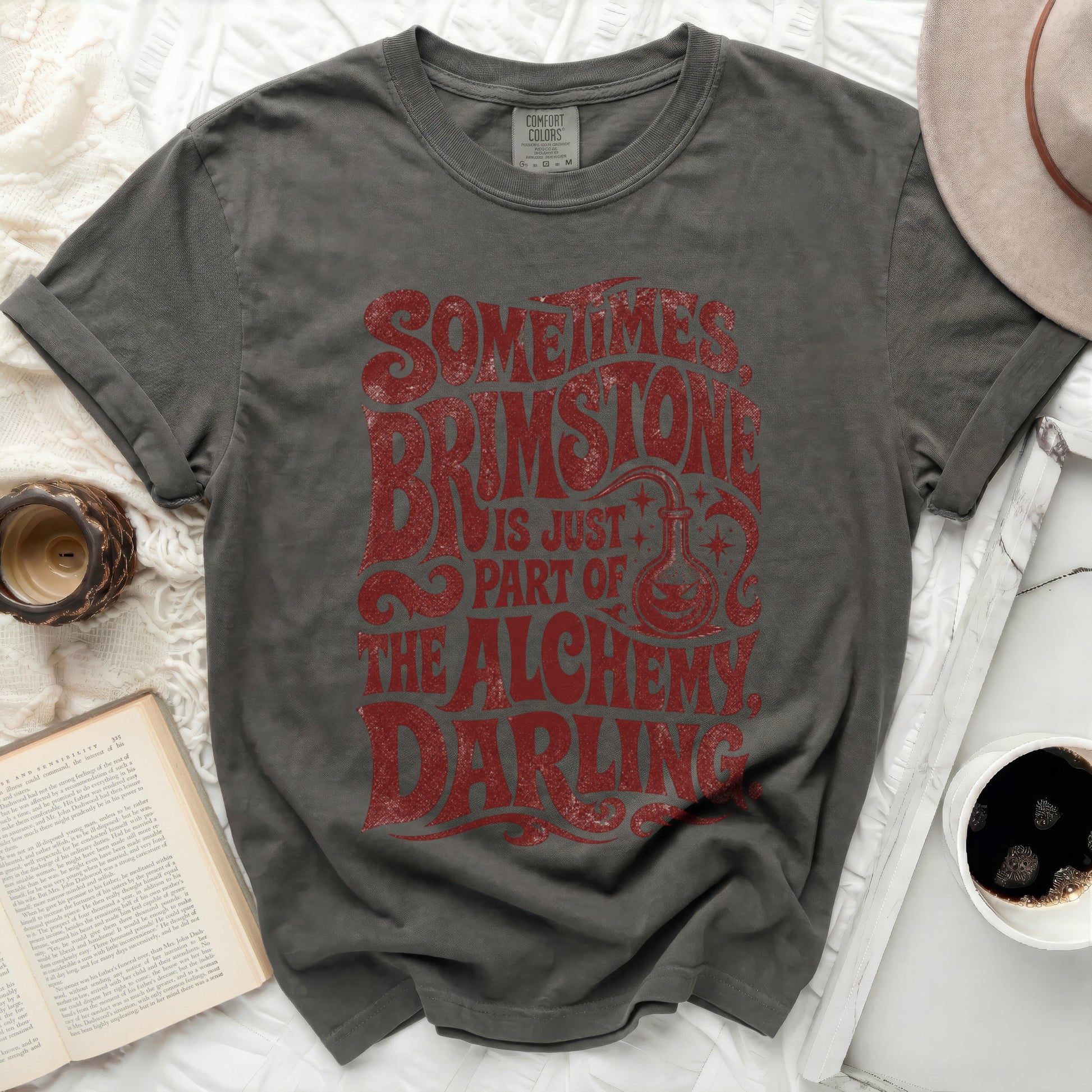 Dark gray t-shirt with "Sometimes Brimstone Is Just Part Of The Alchemy Darling" text.