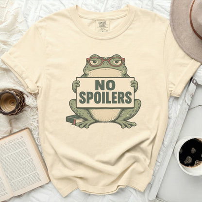 Cream t-shirt with a frog wearing glasses holding a "NO SPOILERS" sign.