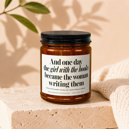 Amber jar candle with "And one day the girl with the books became the woman writing them" text.
