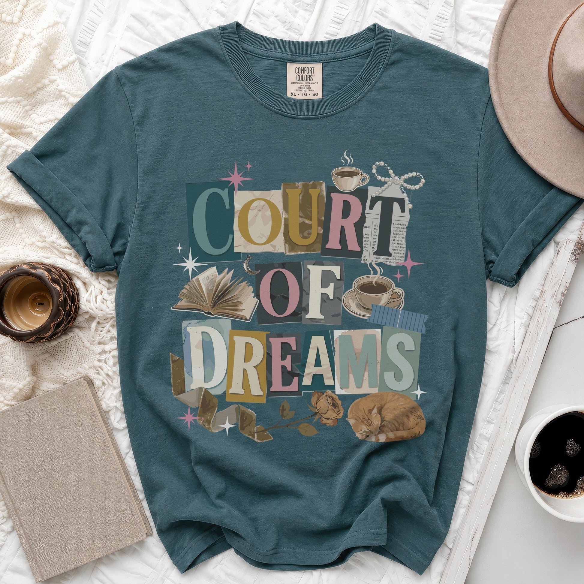 Teal t-shirt with "COURT OF DREAMS" graphic featuring collage elements, a cat, and books.