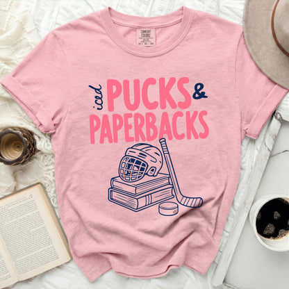 Pink t-shirt with "Pucks & Paperbacks" text, hockey stick, helmet, and books.