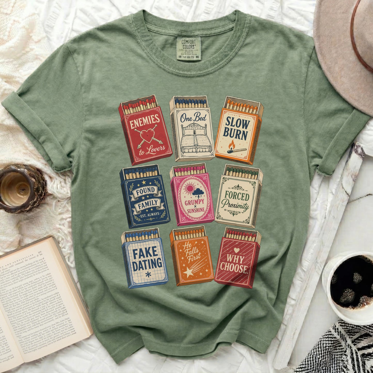 Graphic tee with matchboxes featuring romance novel titles like "Enemies to Lovers."