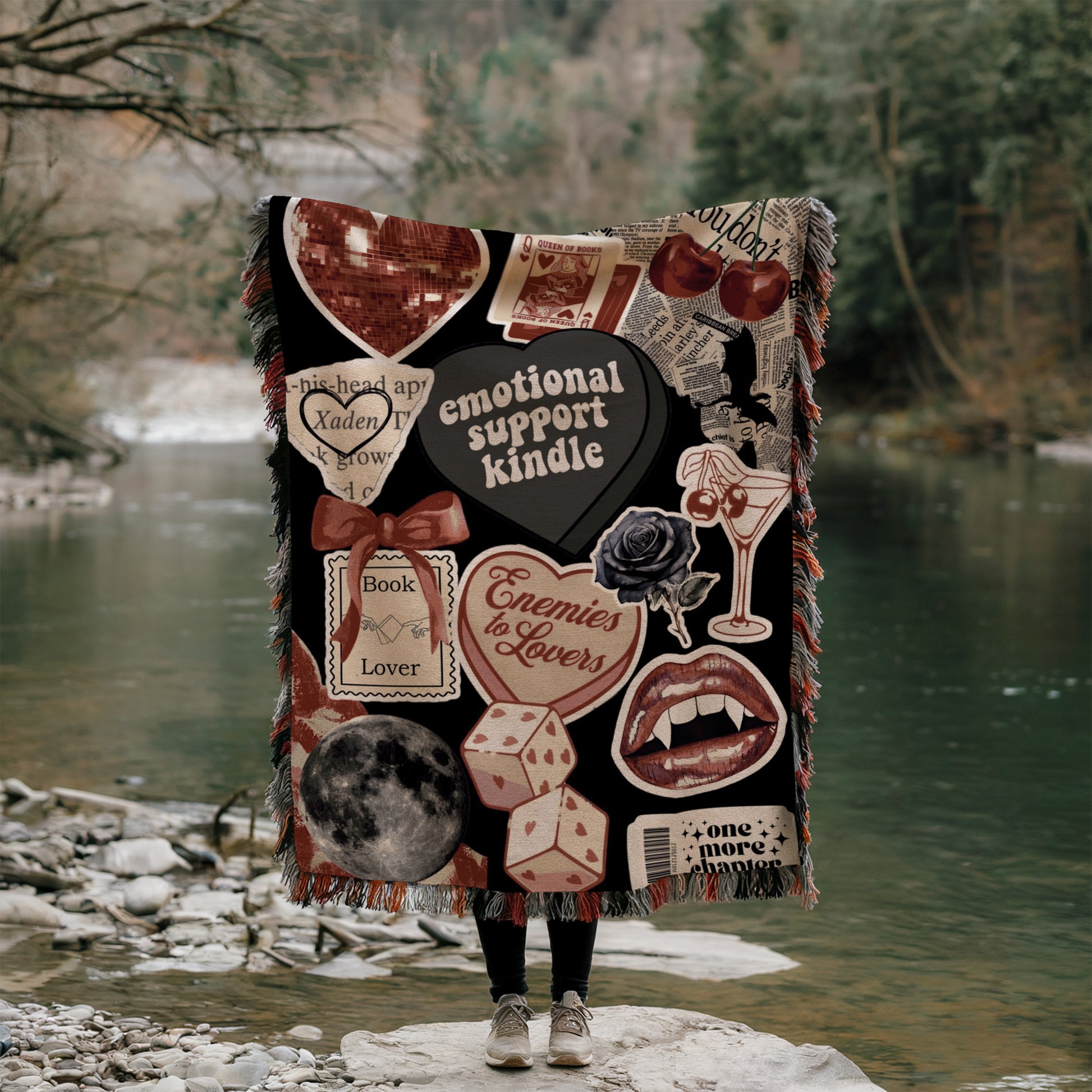 A person is standing on a rock, holding a blanket that is decorated with various images and text, including a heart, a rose, a book, and other symbols.