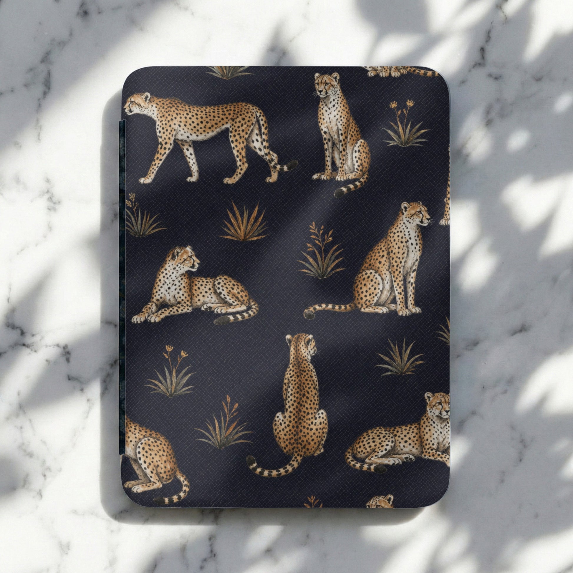 Dark blue journal cover with a repeating pattern of illustrated cheetahs and golden grasses.