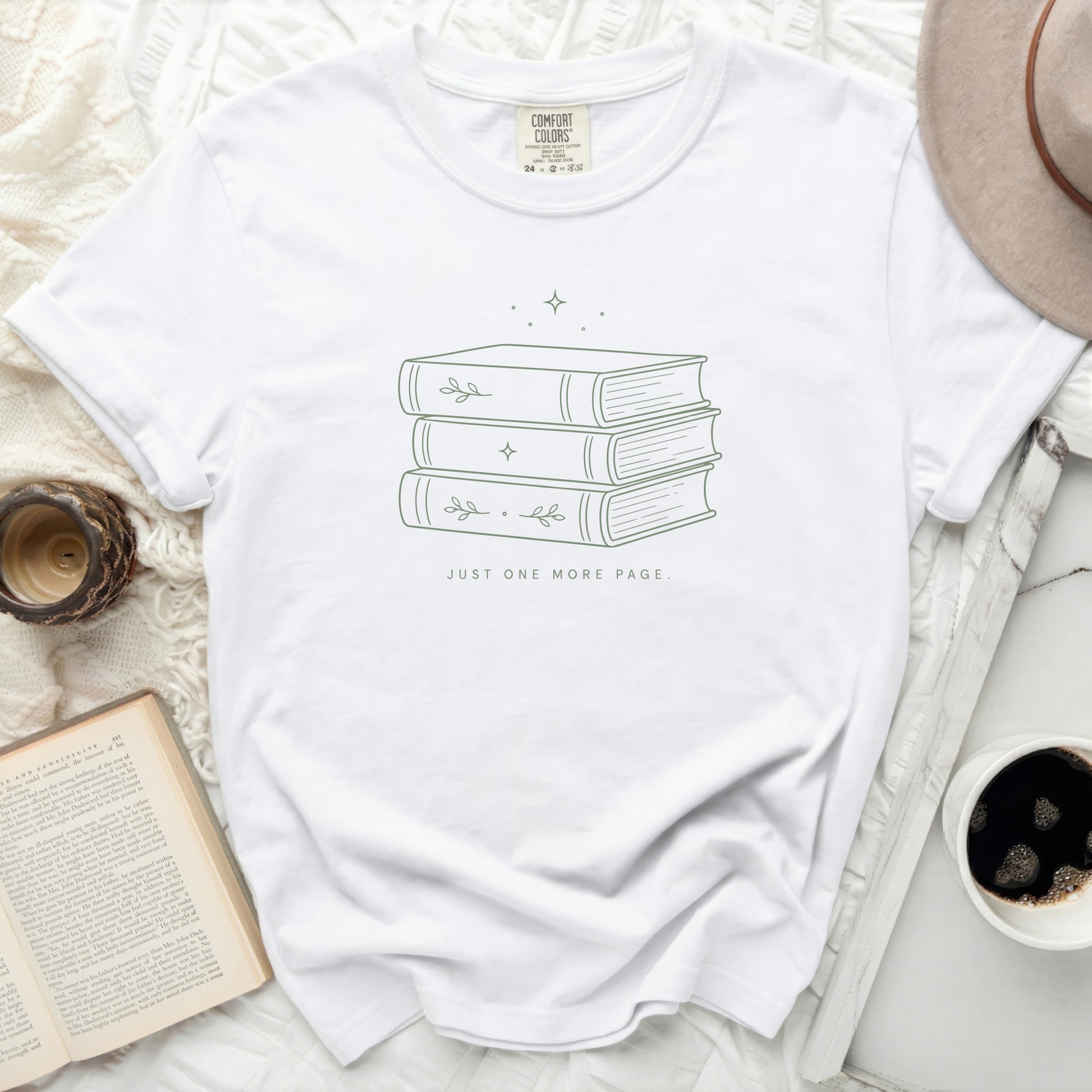 White t-shirt with minimalist stacked books and text "JUST ONE MORE PAGE."