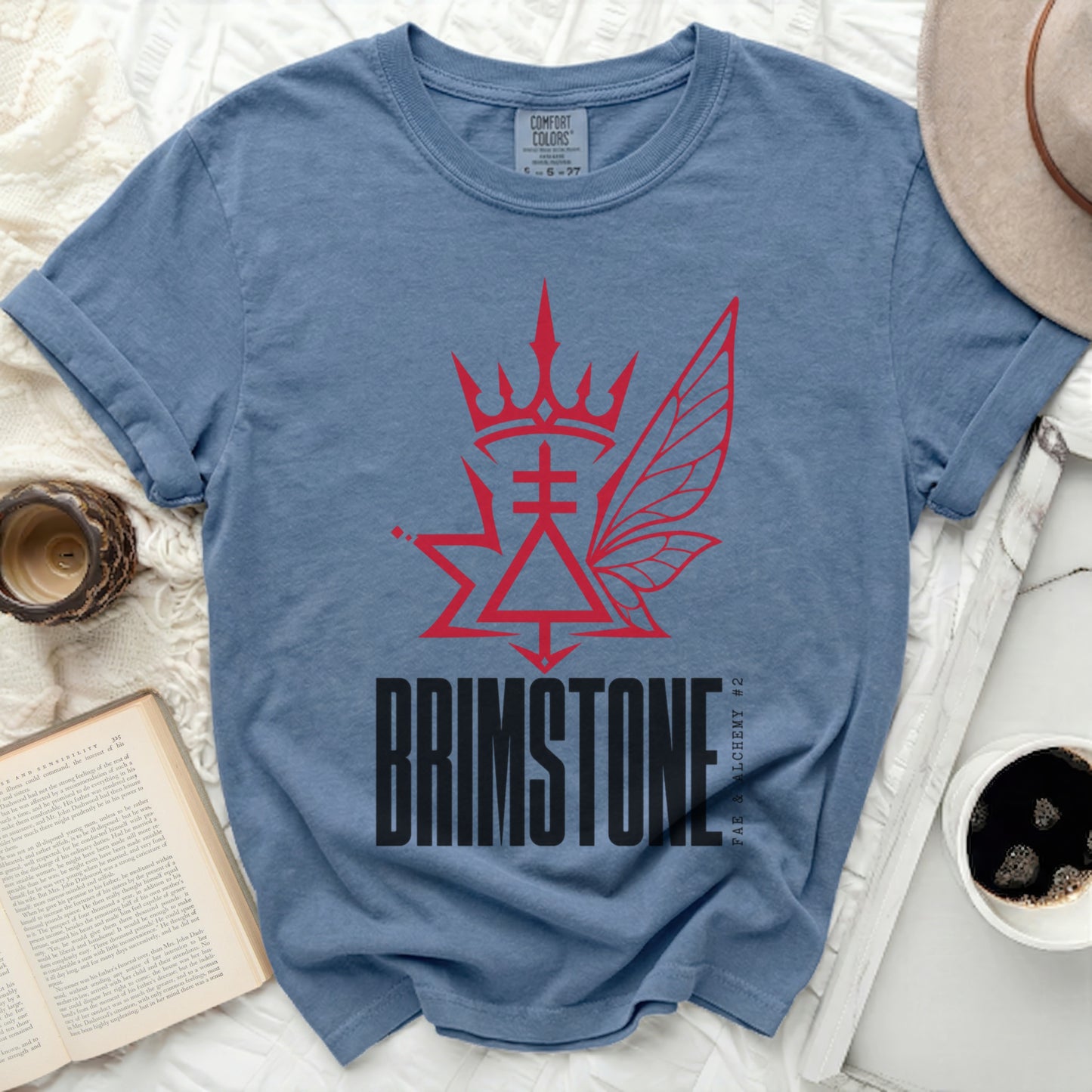 Blue t-shirt with a red brimstone and fairy wing graphic and text.
