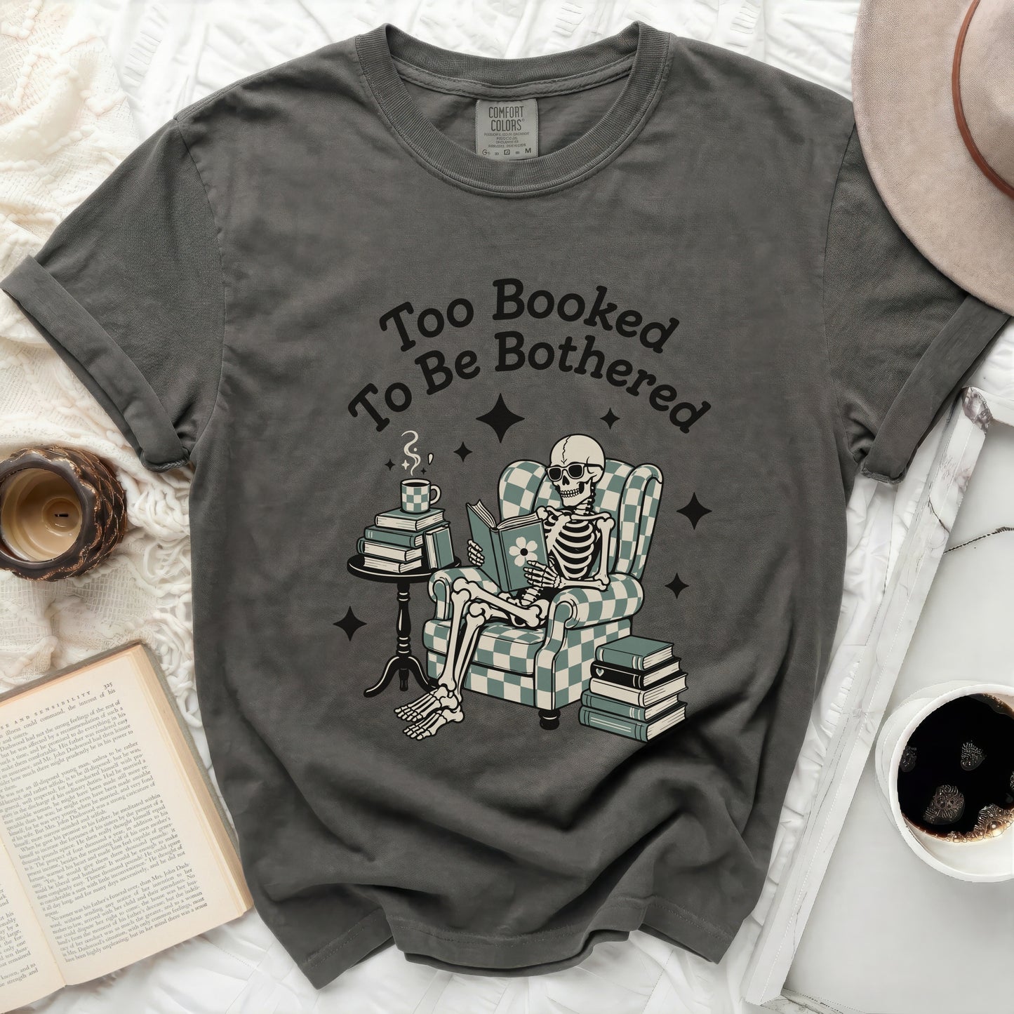 Dark grey t-shirt with "Too Booked To Be Bothered" text, reading skeleton.