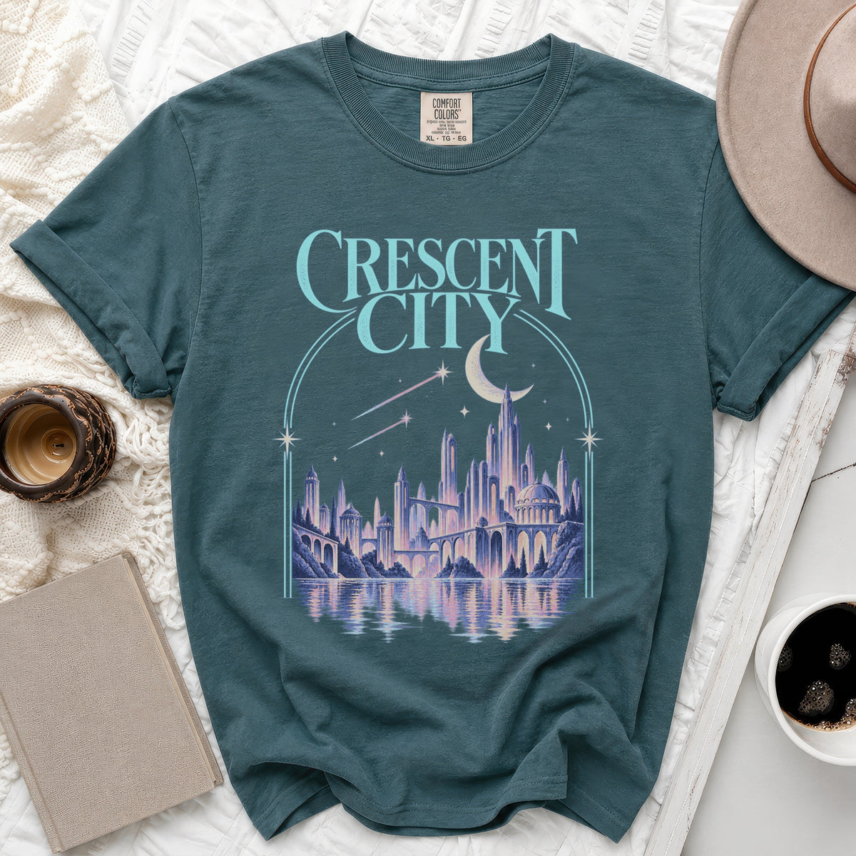 Teal t-shirt with "Crescent City" text and futuristic cityscape graphic.