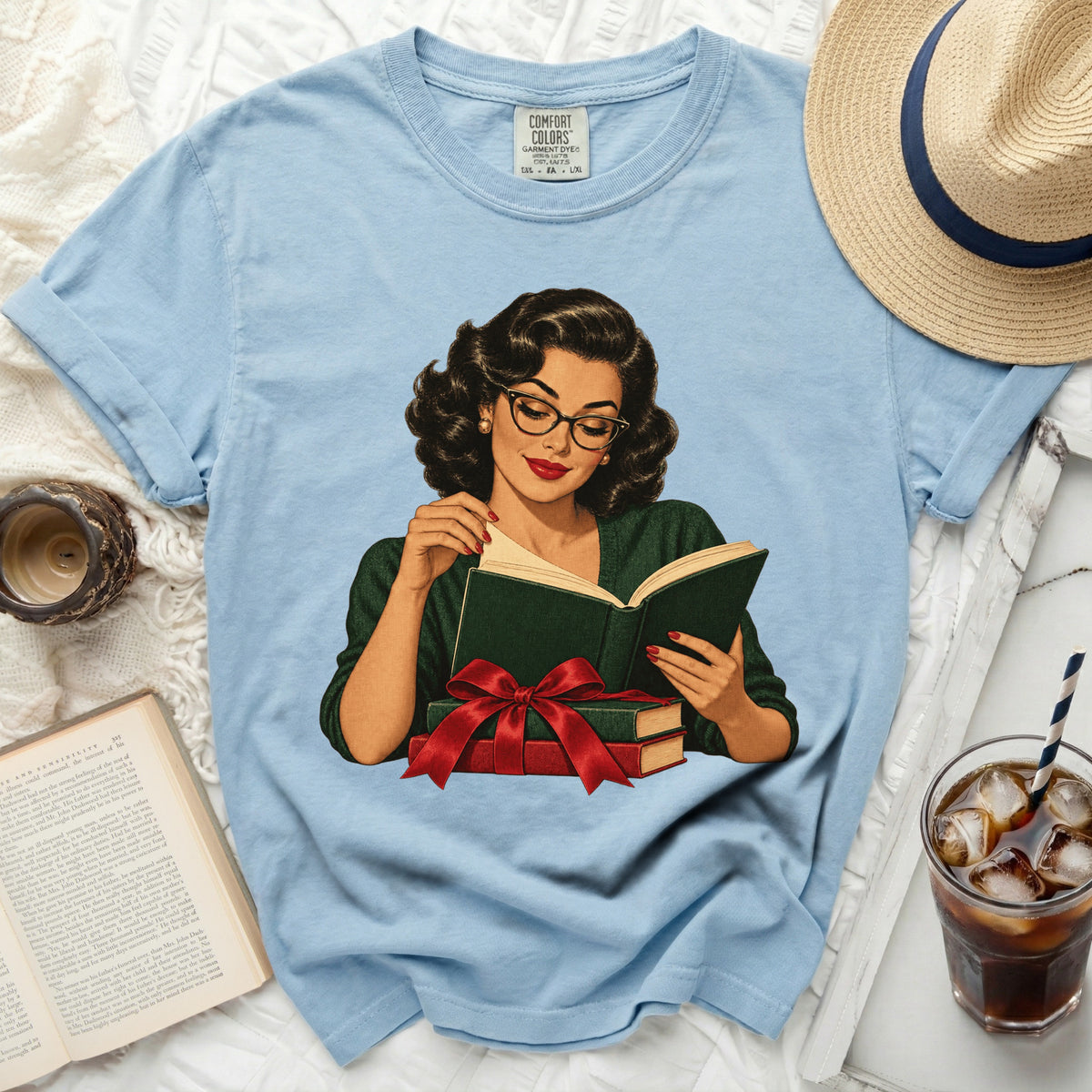 Light blue t-shirt with graphic of woman reading, holding books with red bow.