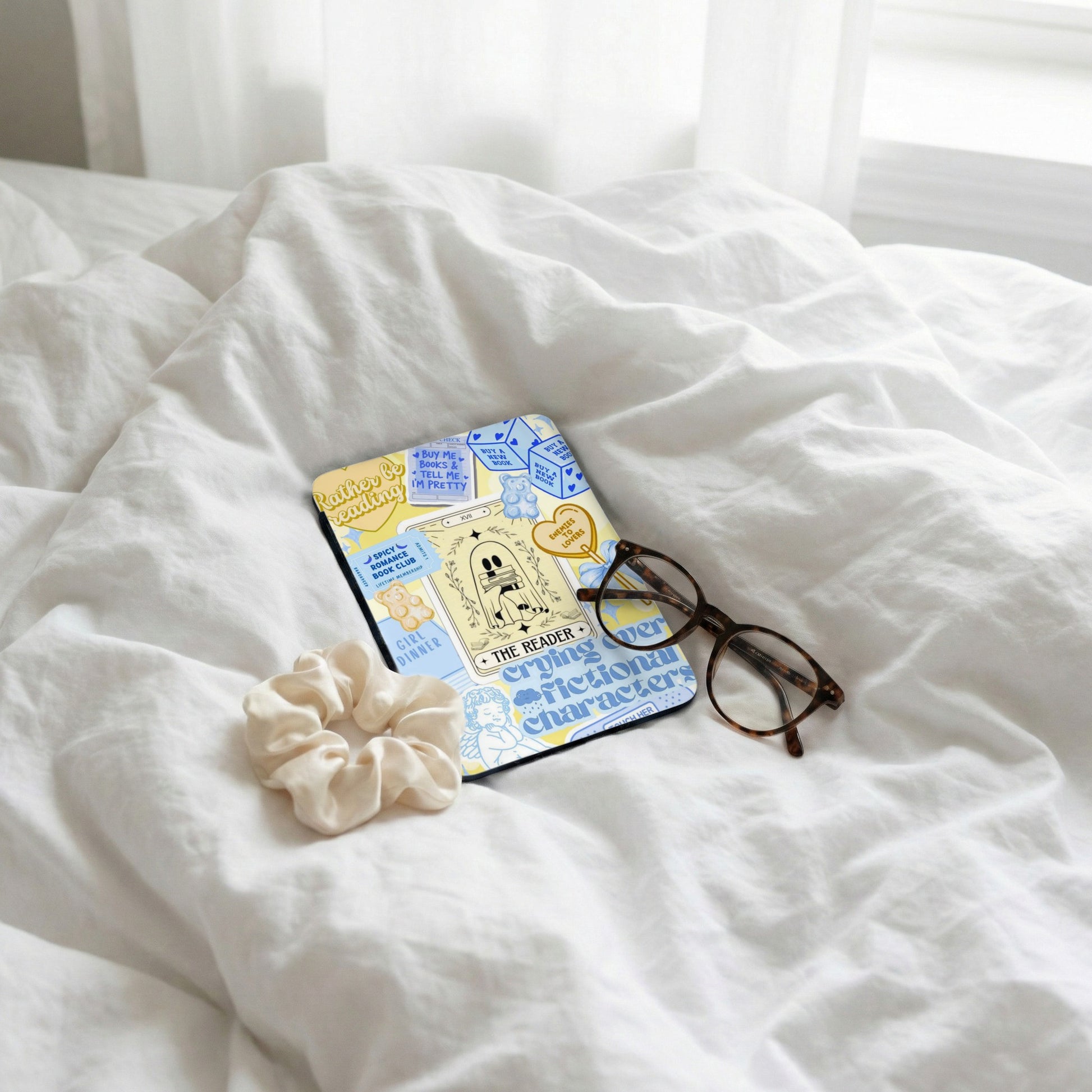 Book-themed coaster with glasses, scrunchie on white bedding.