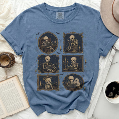 Blue t-shirt with multiple frames of skeletons reading books and enjoying company.