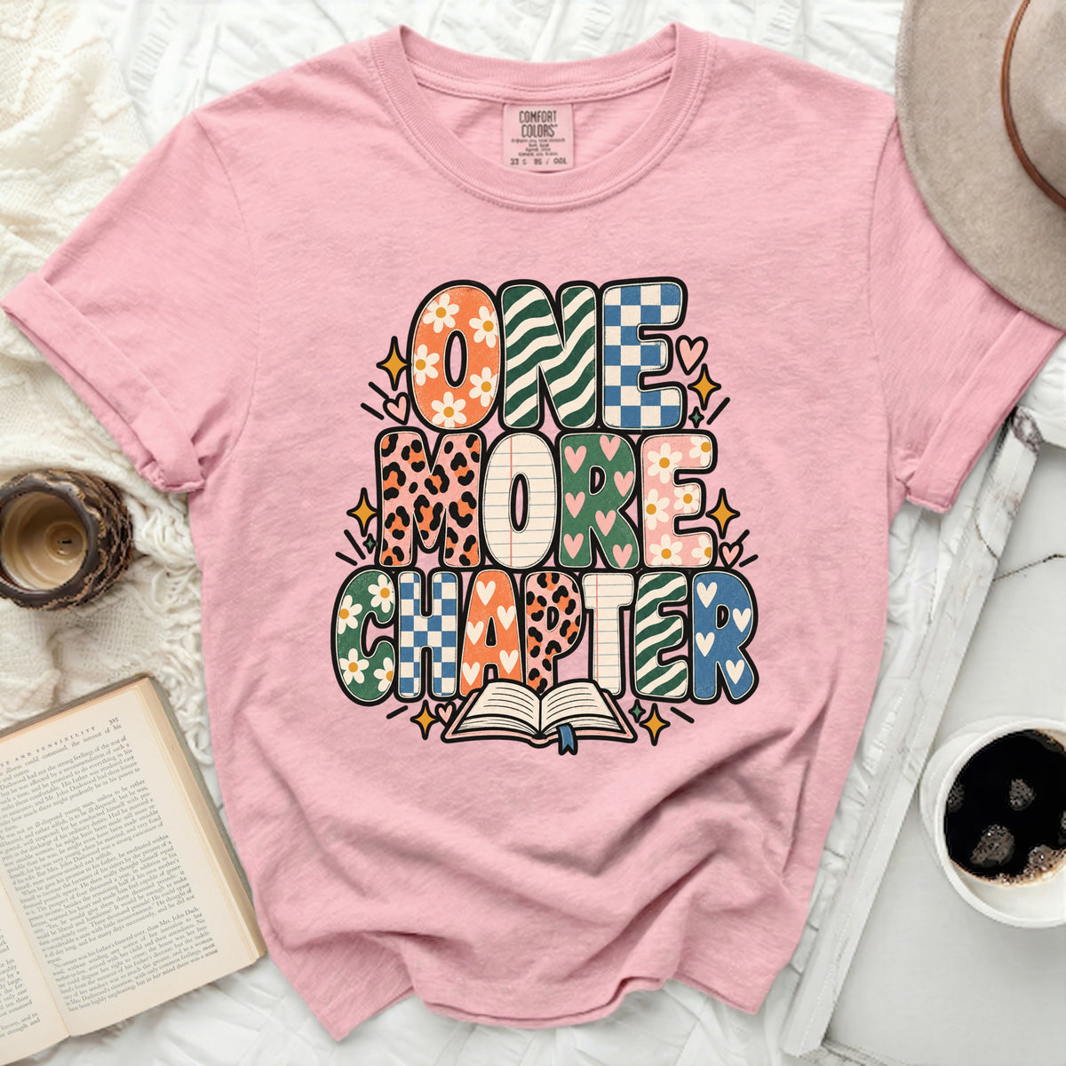 Pink t-shirt with "ONE MORE CHAPTER" text and an open book graphic.
